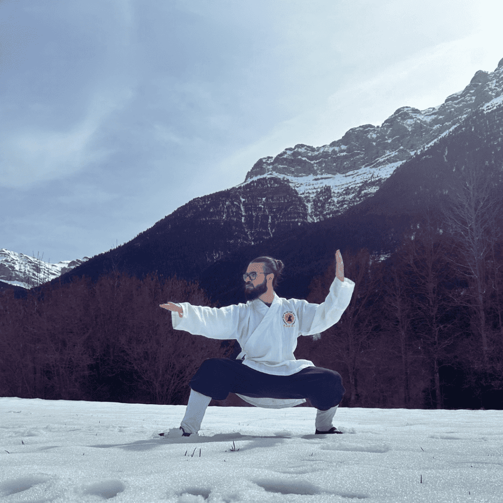 2 Mestre de Kung Fu i Taichi practicant a la neu amb muntanyes de fons