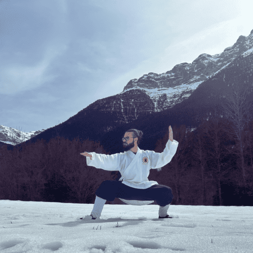 Mestre de Kung Fu i Taichi practicant a la neu amb muntanyes de fons