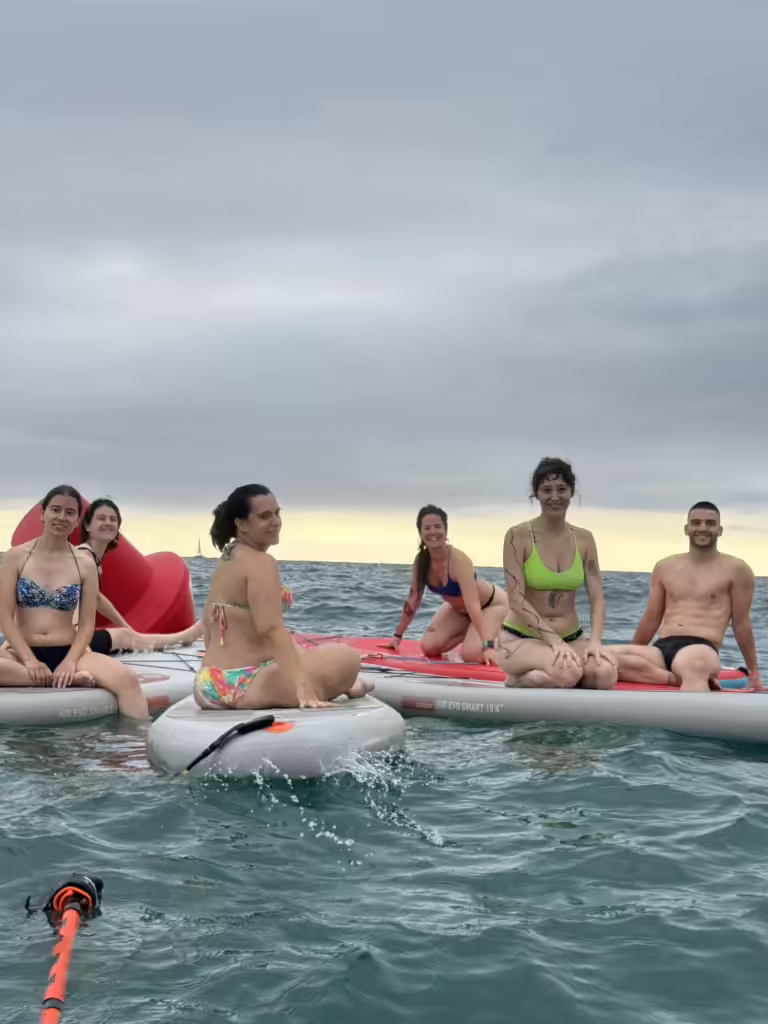 La comunitat OMTAO fent Sup Yoga a la platja de Badalona